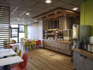 a restaurant with tables and chairs and a kitchen at ibis budget Tours Centre Gare et congrès in Tours