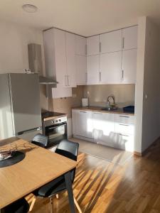 a kitchen with white cabinets and a table and chairs at Apartman Park in Stara Pazova