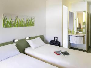 a bedroom with two beds with a sink and a mirror at ibis budget Lyon Est Chaponnay in Chaponnay