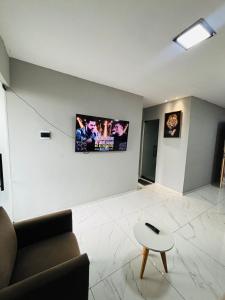 a living room with a couch and a tv on the wall at Flats Sucesso in Teresina