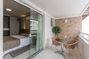 a bedroom with a bed and a table and chairs at Hotel Gumz in Balneário Camboriú