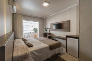 a hotel room with a bed and a television at Hotel Gumz in Balneário Camboriú