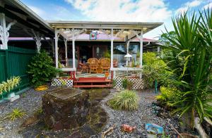 une maison dotée d'une terrasse couverte avec des chaises. dans l'établissement Hale Kawehi Guesthouse, à Hilo