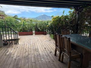 a wooden deck with chairs and a table and mountains at Chez Charline in Saint-Claude