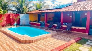 a swimming pool with a wooden deck and a house at Casanostra44 in Genipabu