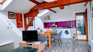 a living room with a tv and a table with chairs at Chambres Du Petit Bonheur in Biscarrosse