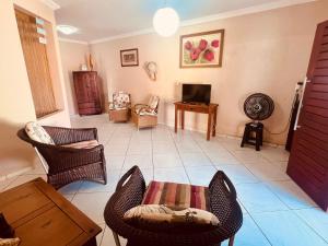 a living room with chairs and a table and a tv at Casanostra44 in Genipabu
