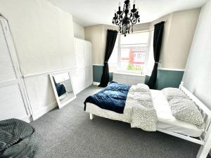 a bedroom with a bed with a chandelier and a window at New Brighton Beach in Wallasey