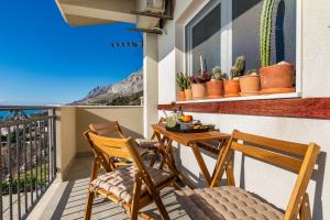a balcony with two chairs and a table with a view of the ocean at Mimice Hills Luxury Penthouse 229 m2, Panoramic Wrap Terrace, Jacuzzi,BBQ in Mimice