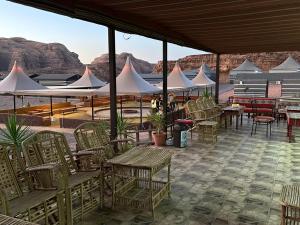 a patio with chairs and tables and white tents at Hillawi Private Desert Camp in Aqaba