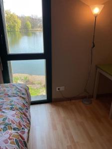 a bedroom with a window with a view of a lake at Logement au bord de l eau in Dordives