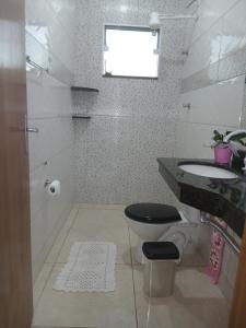 a bathroom with a toilet and a sink and a window at Quarto Rustico em Alfenas in Alfenas