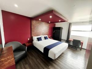 a hotel room with a large bed and a chair at Hotel Rose Ensenada in Ensenada