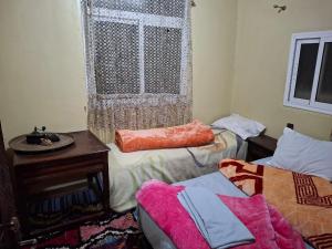a room with two beds and a table and a window at Auberge Toubkal Amsouzart Aitst Idar in Tizgui +55 photos