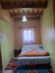 a small bedroom with a bed with a window at Auberge Toubkal Amsouzart Aitst Idar in Tizgui