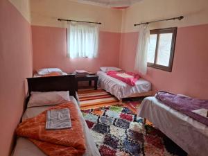 a room with three beds and a table at Auberge Toubkal Amsouzart Aitst Idar in Tizgui