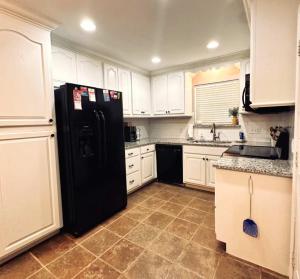 a black refrigerator in a kitchen with white cabinets at Mendoza Villa - Longview Tx in Longview