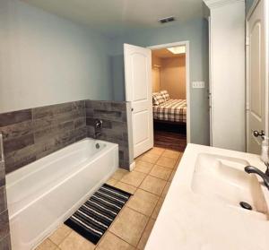 a bathroom with a tub and a sink and a bedroom at Mendoza Villa - Longview Tx in Longview