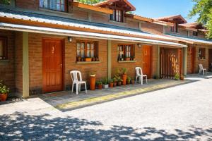 a brick house with two white chairs on a patio at Cabaña LOW COST in El Bolsón