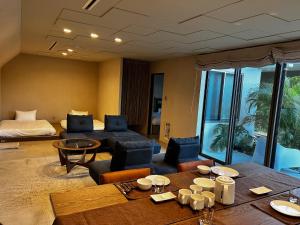 a living room with a table and chairs and a bed at ERUMAYA Resort in Motobu