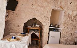 a kitchen with a stone wall with two tables and a refrigerator at Villa Trullo Septis in Ostuni