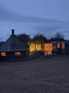 a cabin with a lit up roof and a building at Bridie -rose rural shepherd hut , sleeps 4 with wood fuel hot tub -mini safari -on your doorstep small exotic animals in Kington