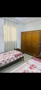 a bedroom with two beds and wooden cabinets at Appartement 2 chambre in Gabès