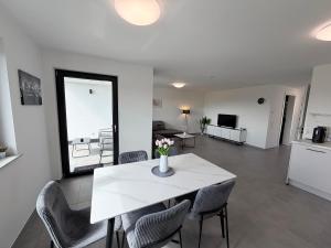 a living room with a white table and chairs at BILEANCA - Neubau-Ferienwohnungen Rheinhausen Europa-Park in Rheinhausen +14 photos
