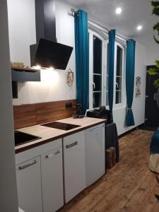 a kitchen with white cabinets and blue curtains at Chambre d'hôtes studio proche mer Mers-les-bains in Gamaches