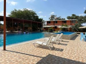 two white chairs sitting next to a swimming pool at Hospedaje Los Pecanos in Ica