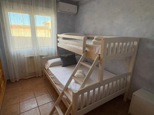 two bunk beds in a small room with a window at Casa Tío Tato , cerca de Puy du Fou y Toledo in Polán
