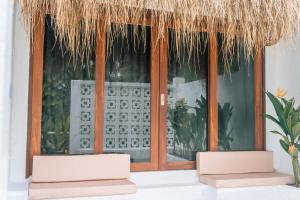 Zwei Stühle vor einem Fenster mit Strohdach in der Unterkunft Casa Oro in General Luna + 10 Fotos