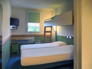a room with two beds and a desk and a bunk bed at ibis budget Niort - La Crèche in La Creche