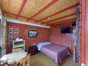 a bedroom with a bed and a brick wall at Casa Hospedaje el Prado Eco turismo in Oxapampa