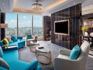 a living room with blue furniture and a large window at Sofitel Guiyang Hunter in Guiyang