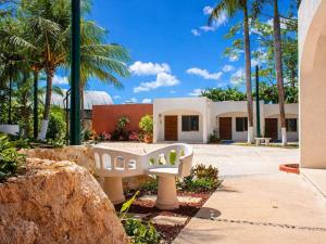 a white bench in front of a building with palm trees at Solanza Hotel Hacienda in Cancún