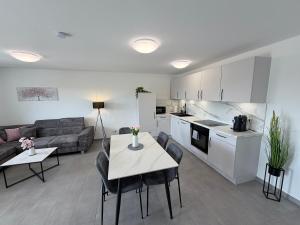 a kitchen and a living room with a table and chairs at BILEANCA - Neubau-Ferienwohnungen Rheinhausen Europa-Park in Rheinhausen