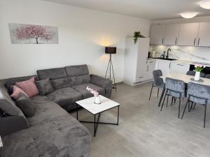 a living room with a couch and a table and a kitchen at BILEANCA - Neubau-Ferienwohnungen Rheinhausen Europa-Park in Rheinhausen