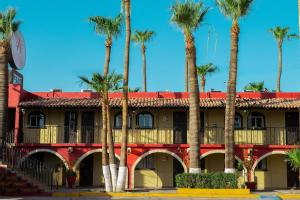 a red building with palm trees in front of it at Hacienda del Indio in Mexicali