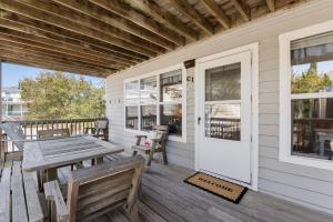 a porch with a wooden table and benches on a house at Happy Ours in Corolla