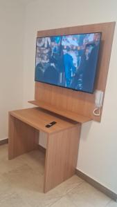 a flat screen tv sitting on top of a wooden stand at Casa da Dinda 202 in Rio das Ostras