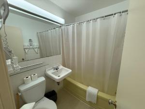 a white bathroom with a toilet and a sink at Lake-Vu Motel in Kenora