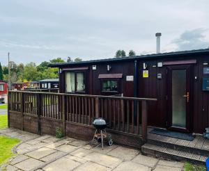 a house with a deck with a grill on it at Afon Lodge in Maesmynis