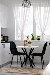 a white kitchen with a table and two chairs at White Pearl Residence in Roşu