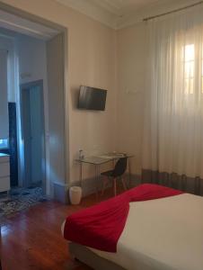 a bedroom with a bed and a table and a television at Palacete Suite Aveiro in Aveiro