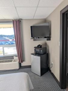 a hotel room with a bed and a tv and a room at Beaver Motel in Wawa