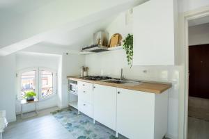 a white kitchen with white cabinets and a sink at Elegante Attico Fronte Lago - Casa Barozzi in Luino