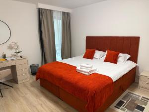 a bedroom with a bed with orange blanket and a desk at IDDA Concept 2 dormitoare 2 și living in Târgu-Mureş