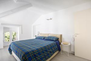 a white bedroom with a bed with a blue blanket at Elegante Attico Fronte Lago - Casa Barozzi in Luino +15 photos