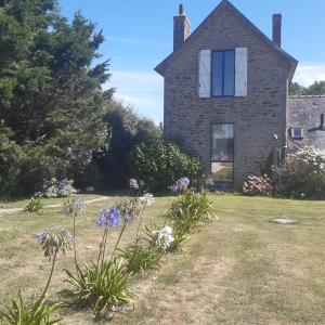 an old stone house with flowers in the yard at Les gîtes de Tréguennec in Tréguennec